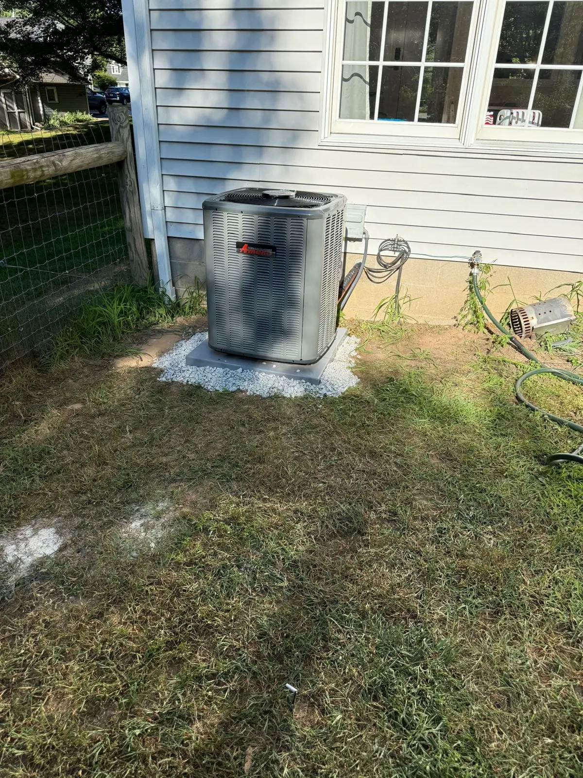 High-efficiency outdoor AC condenser installed beside a home in Fairport, NY 14450 by MGM Heating & Cooling.