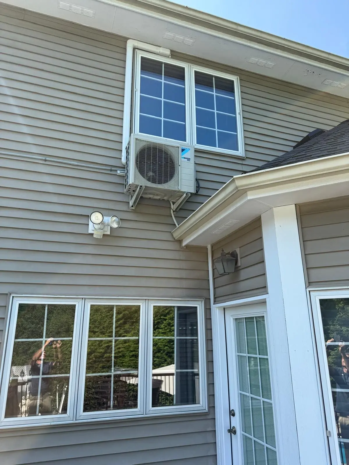 Outdoor ductless mini-split unit installed on a two-story home in Penfield, NY by MGM Heating & Cooling.