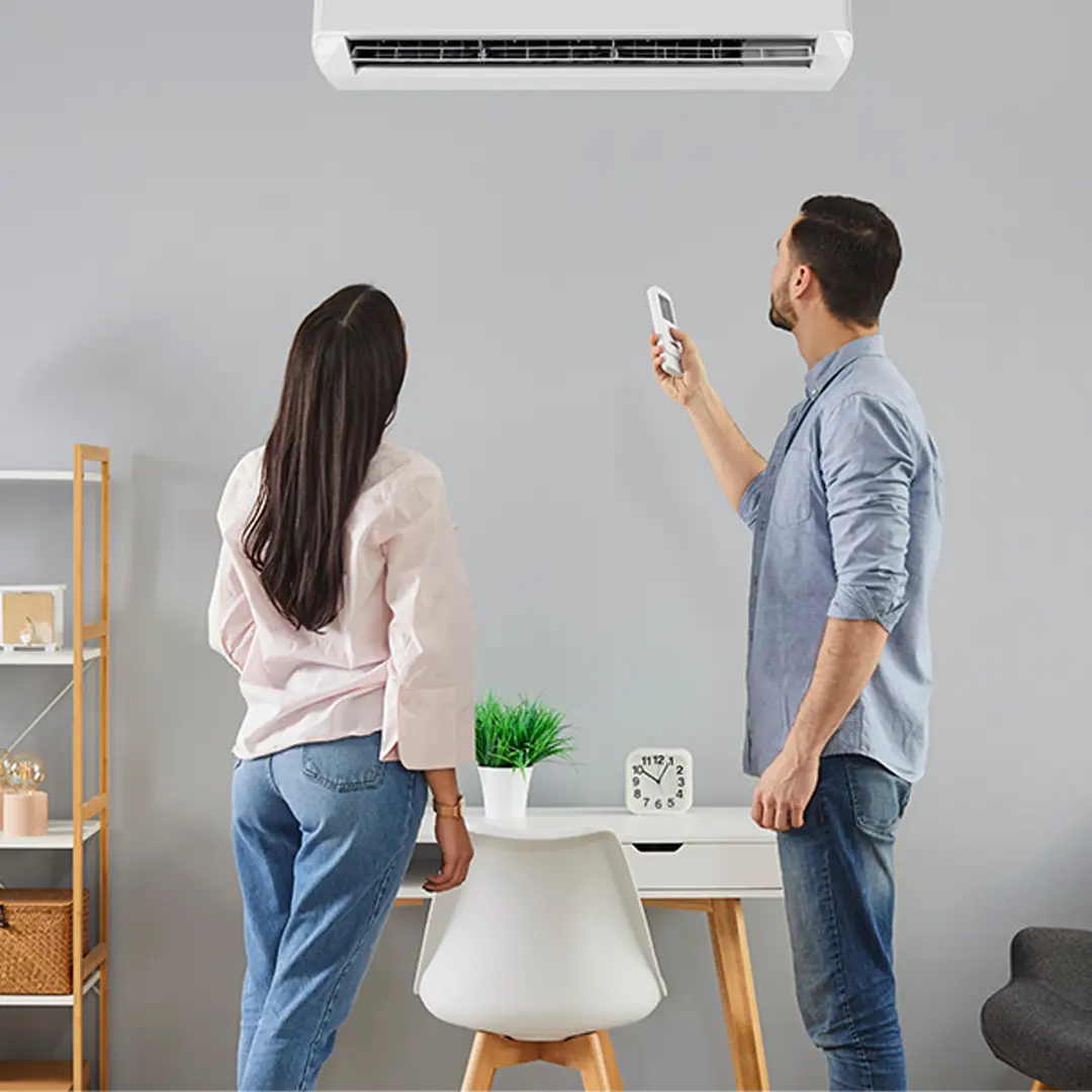Couple adjusting remote for wall-mounted air conditioner at home